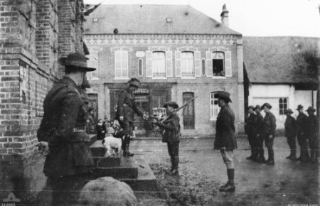 Feuquieres, France. 3 January 1919. Presentation of medals by Commanding Officer (CO), 35th Battalion to C Company (Coy) "soccer" team, winners of inter-company football competition played at Merelessart Chateau, on steps of the Mairie [Town Hall] in the village square. Left to right: Major H. J. Connell DSO MC & Bar, Second in Charge; Lieutenant Colonel H. F. White DSO Croix de Guerre, CO; Private (Pte) D. Lee; Captain R. V. Lathlean MC & Bar, OC C Coy; Corporal (Cpl) H. Randall; Cpl L. Whittaker; Pte Yarrow; Lance Corporal J. Mitchell; Pte J. Thraves. At left, foreground, is "Chick" the mascot of the Battalion transport section presented by a Flemish woman in January 1917 at Pont De Nieppe.